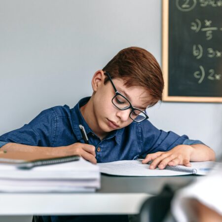 Boy writing in notebook at school